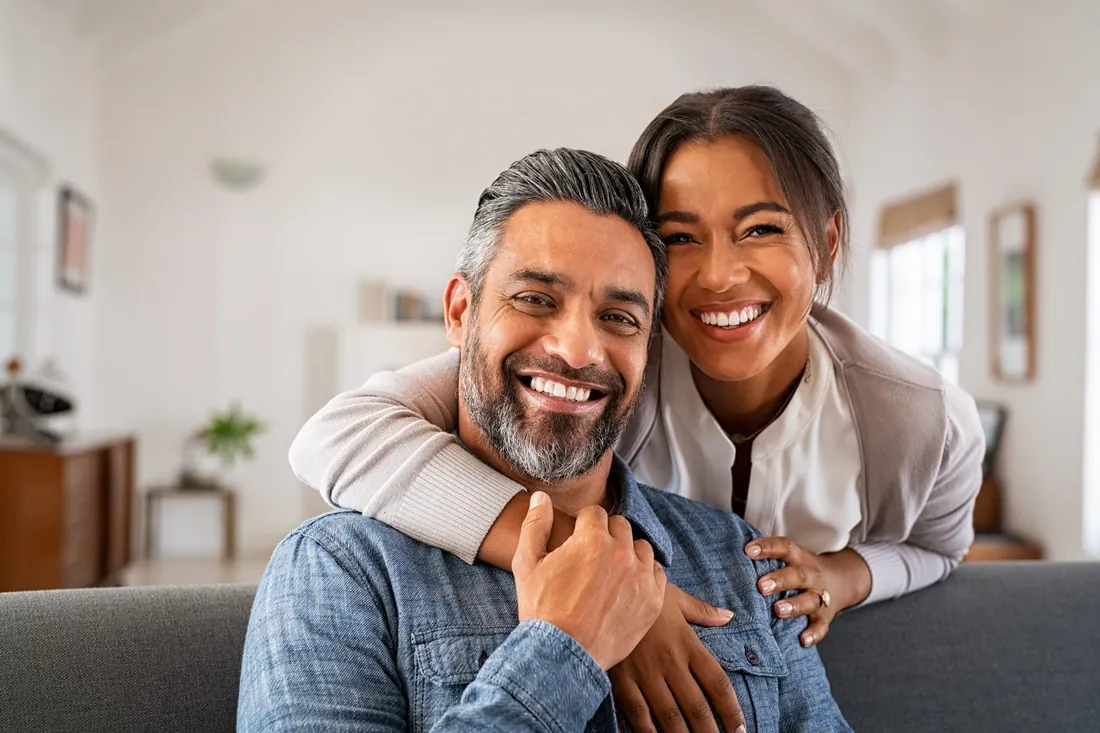 Smiling couple at home after dental implant treatment